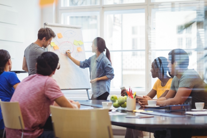 Business executives discussing with their colleagues on whiteboard during meeting at office